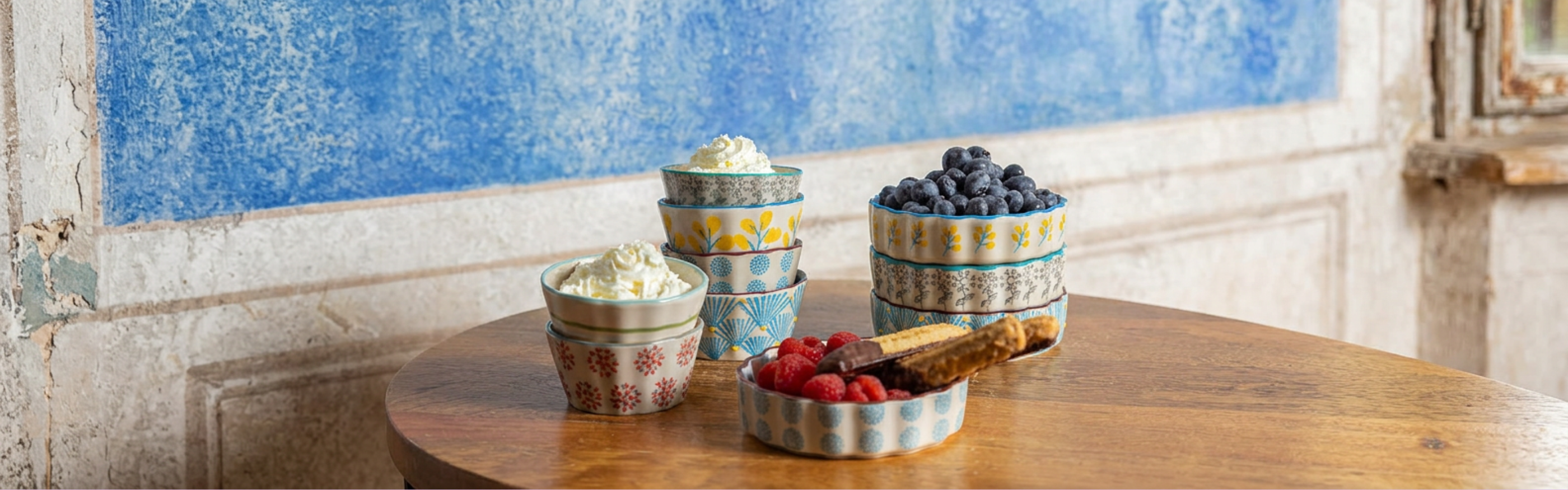Bunte Keramikschalen von Tranquillo mit Beeren und Sahne auf Holztisch – nachhaltige Wohnaccessoires
